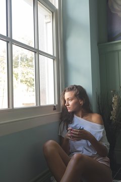 Woman sitting near window while having coffee