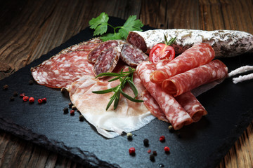 Food tray with delicious salami, ham,  fresh sausages and herbs. Meat platter with selection