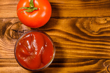Ripe tomatoes and ketchup on wooden table. Top view