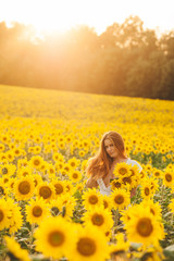 Fototapeta na wymiar Beautiful girl in a huge yellow field of sunflowers.