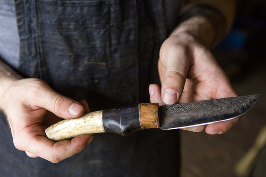 Midsection of blacksmith holding knife while standing in workshop