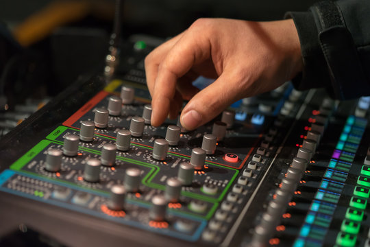 Sound technician turns buttons of the mixer