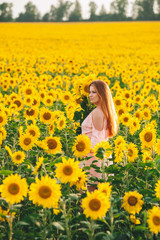 Fototapeta premium Beautiful girl in a huge yellow field of sunflowers.