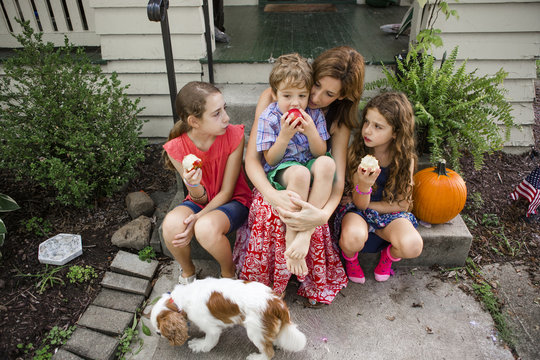 High angle view of children eating apples while sitting with mother on steps