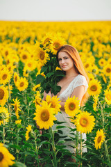 Obraz na płótnie Canvas Beautiful girl in a huge yellow field of sunflowers.