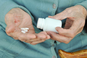 an elderly woman with a cane holding a pill and a container on the street. Health.Mockup. Close up.