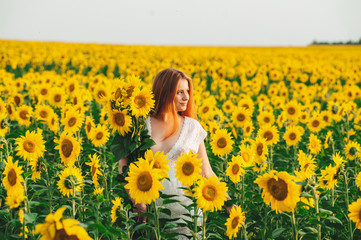 Fototapeta premium Beautiful girl in a huge yellow field of sunflowers.
