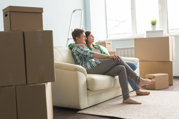 Moving, new things, people concept - happy couple in love sitting in an empty apartment among boxes and dream about future