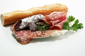 Food tray with delicious salami, ham,  fresh sausages and herbs. Meat platter with selection