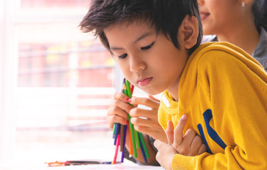 Asian boy is drawing in kindergarten art classroom