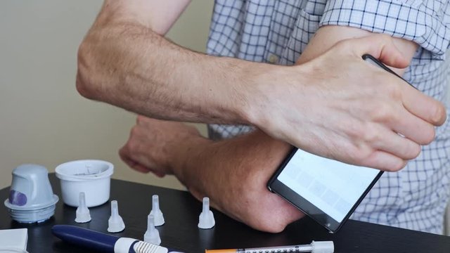 A man hands brings to the hand the smartphone for measuring glucose in the blood