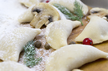 Traditional Russian food dumplings or vareniki, dough with meat or other stuffing, with flour and egg served on a table with sour cream, mushrooms and fresh vegetables, garlic sauce. traditional