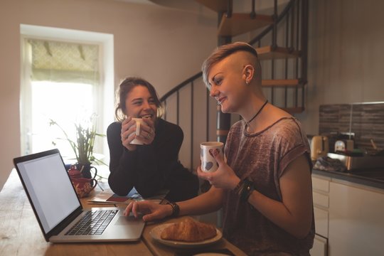 Lesbian couple using laptop while having coffee