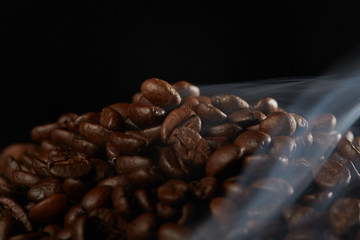 grains of coffee with smoke on a dark background