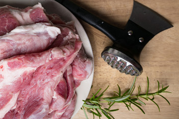 Fresh raw pork pieces on cutting wooden board with metal butcher