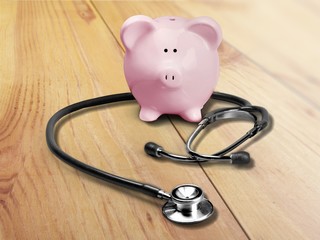 Piggy bank with stethoscope on blue background