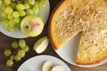 Freshly baked apple pie rustic, dark wood background. Autumn fruits: grapes, apples, nuts. Still life dessert homemade food, top view.