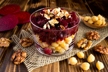 Vegetarian salad with chickpea,beet  and walnuts in the glass jar on the  rustic wooden   background
