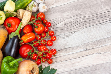 Colourful variety of fresh home grown vegetables from an organic garden on a wooden surface. Tomato, green and yellow bell peppers, carrot, parsley, onion, garlic, potato, eggplant and zucchini.