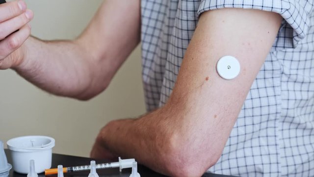 A man brings to the hand the reading device to the sensor for measuring glucose