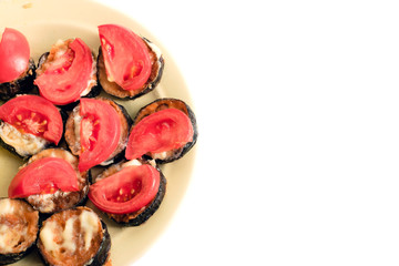 Sliced tomatoes and eggplant on a plate on a white background. There is free space for your inscription