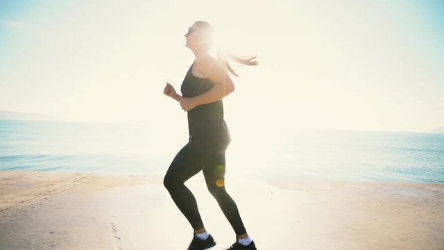 Healthy young woman running on the seaside on sunrise