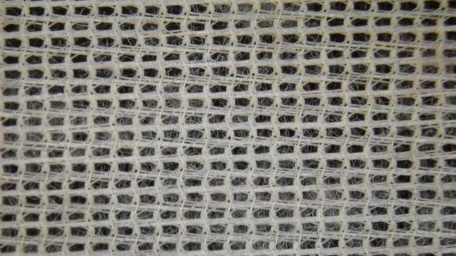 Microscopic view of clothes dryer lint filter with lint cotton fibers and synthetic fibers.