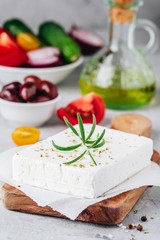 Homemade greek cheese feta with rosemary on wooden cutting board. Ingredients for greek salad