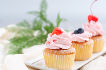 Group of cupcakes arrange on long white plate on table with blur flowers background, dessert bakery in minimal concept.  Bakery advertise in menu.