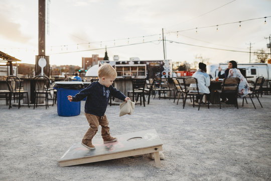 Boy playing cornhole at sidewalk cafe during sunset