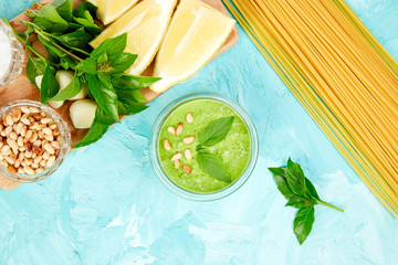 Homemade pesto sauce in glass jar with ingredients.