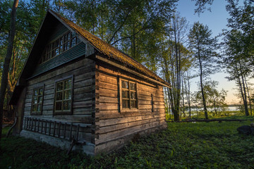 Fototapeta na wymiar Old wooden house on the edge of forest near the lake Svir at sunrise