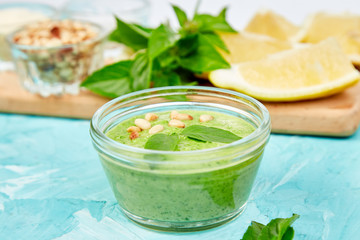 Homemade pesto sauce in glass jar with ingredients.