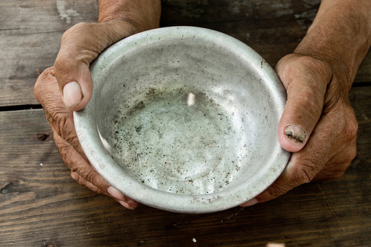The poor old man's hands hold an empty bowl of beg you for help. The concept of hunger or poverty. Selective focus. Poverty in retirement. Alms