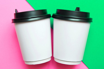 Two disposable cups for hot drinks on a pink and green geometric backgrounds. Trend colors.