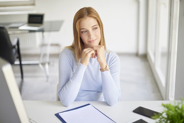 Businesswoman looking thoughtfully while sitting at office desk