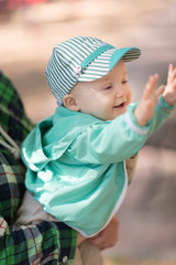 Baby boy and mom outdoor. Boy in a green jacket and cap