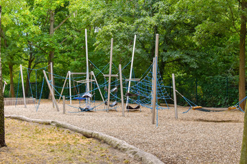 Climbing frame with equipment out of ropes, metal poles and other elements on a public playground in Berlin.