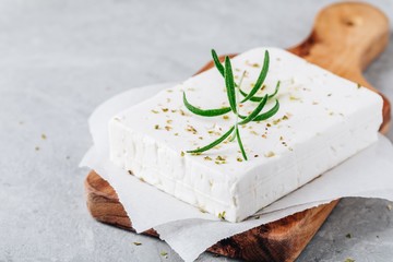 Homemade greek cheese feta with rosemary and herbs on wooden board