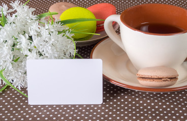 Fototapeta na wymiar Large cup, white flowers and cakes. White card for applying text