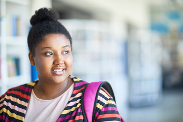 Smiling attractive African-American overweight student with hair bun reflecting about future and looking aside while thinking about university entry - obrazy, fototapety, plakaty