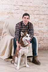 A man and a hussy dog are posing in the studio. The basics of training pets.