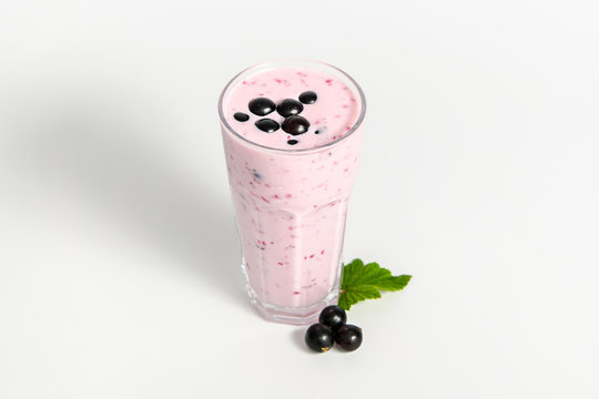 Glass of yoghurt cocktail, smoothies, with berry and leafs of black currant, stands on a white background.