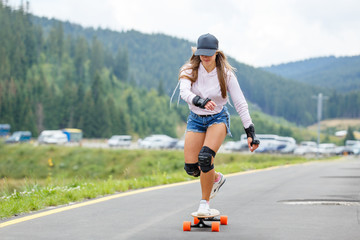 Fototapeta premium Young girl longboarding downhill on the hillside road