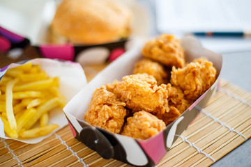 Chicken nuggets with burger and french potatoes on the desk with business papers