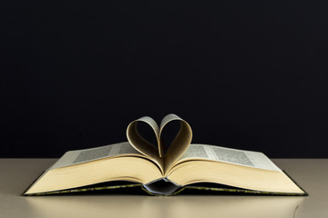 Old open book page in heart shape with library background, love in valentine day concept