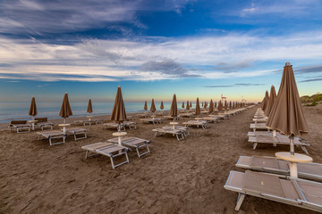 Morning on the beach with empty chaise lounges