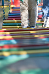 Fototapeta premium Baby's first steps on the playground. bridge of wooden multi-colored boards