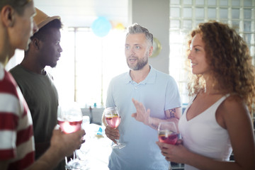 Group of young friends with drinks discussing organization moments before party