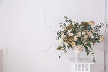 Home interior decor, bouquet of lilacs in a vase and books on rustic wooden table, on a white wall background